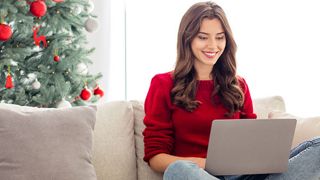 Woman sitting on couch with laptop during Christmas