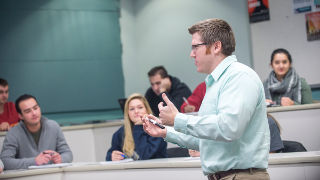 Professor addressing a group of students in a business class.
