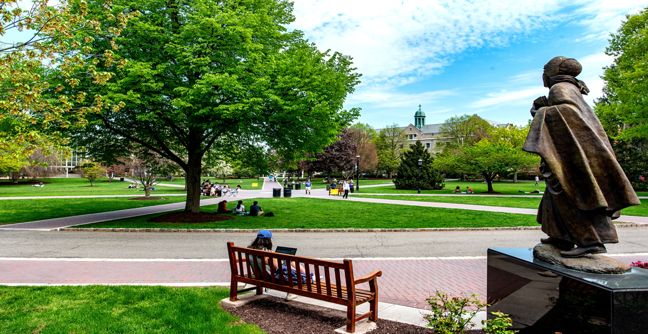 Image of the campus with students sitting on the green and the Mother Seton statue in the right hand corner 