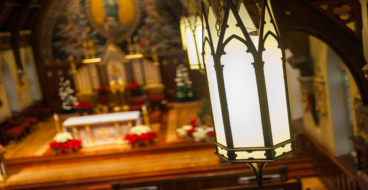 An interior image of the campus chapel at christmas time with a big lantern in the foreground and the altar in the background