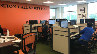 Students at computers with headsets on calling to interview people for Sports Polling. 