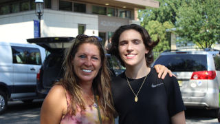 James McCoy standing with his mother in front of Aquinas Hall