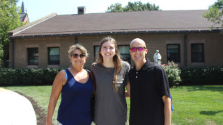 Callie McCool with her parents standing in front of their house