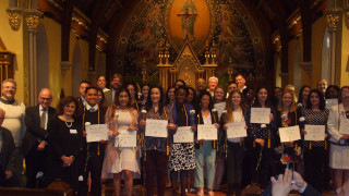 Student standing in chapel with certificates.