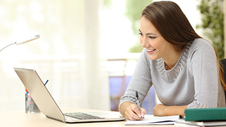 Student looking at laptop with a smile. 