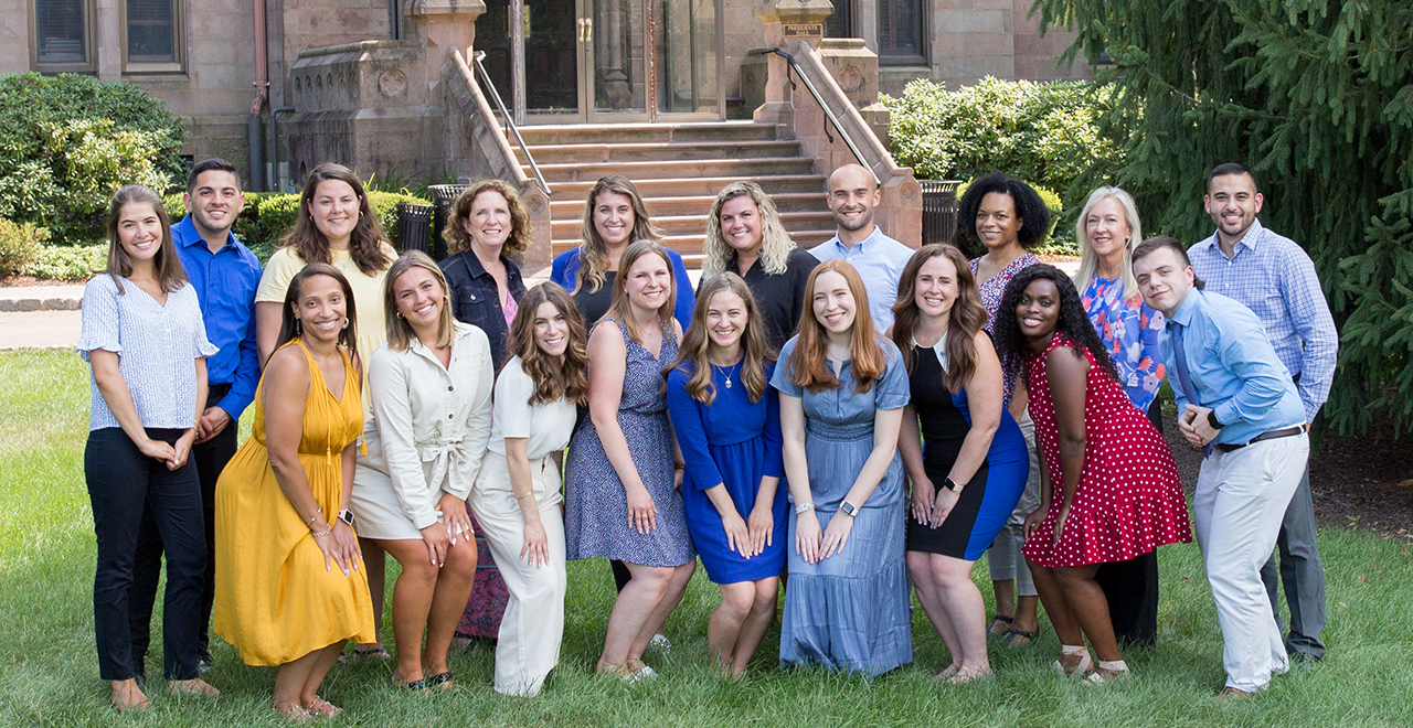 A photo of the admissions counselors team holding a Welcome to Seton Hall sign on the University Green. 