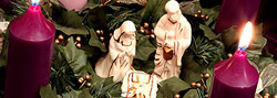 Advent wreath with candles and a nativity scene in the center. 