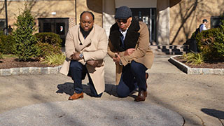 Alvaro Llanos and Shawn Simons Kneeling in front of the Boland Hall Memorial