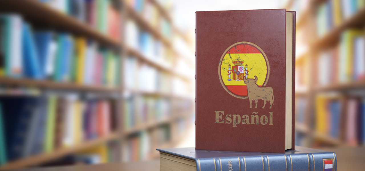 A Spanish textbook with the Spanish flag and a bull on the cover in a library.