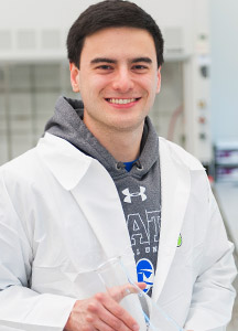 Ben Starke, in his white coat, posing with a beaker