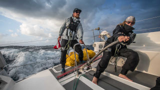 A man and a woman driving a boat on rough waters