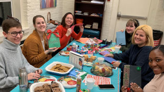 Eight graduate students hold up greeting cards they madeHoliday greeting cards for hospitalized childrenGraduate students enjoying hot chocolate and cookies while decorating cards