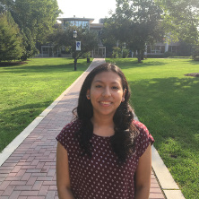 Claudia Valverde on the University Green with a Seton Hall flag and the University Center behind her.