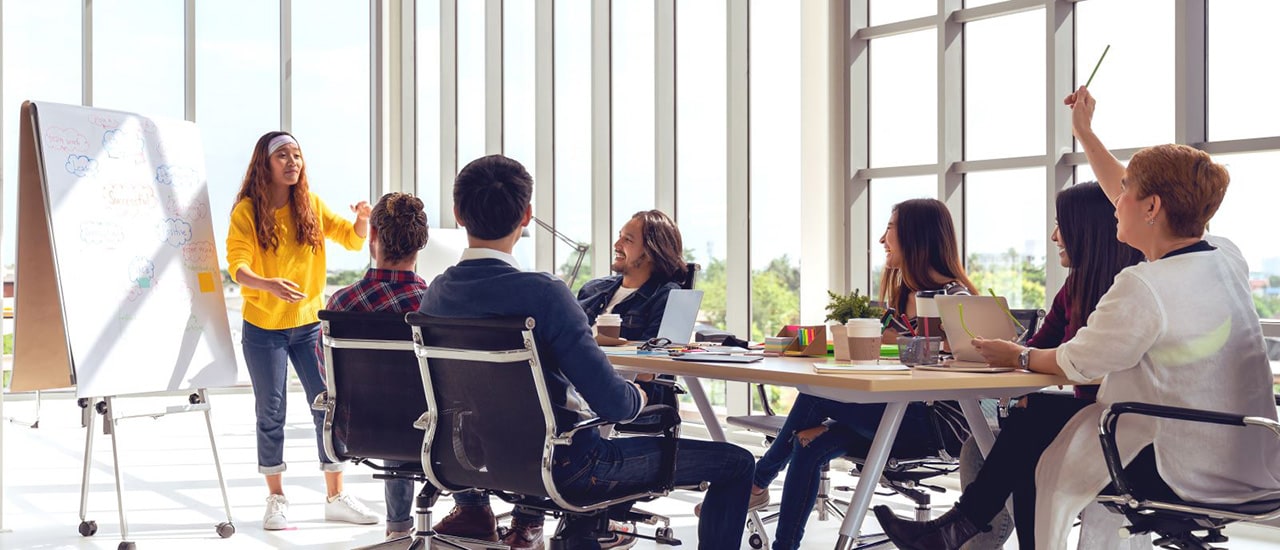 A photo of people around a conference table during a presentation.