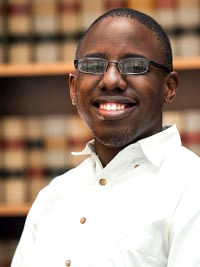 Dwayne Greene standing in front of a book shelf. 