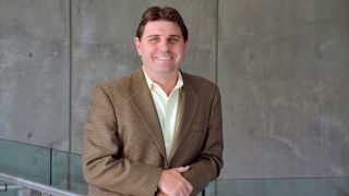 Daniel Ladik in brown suit, smiling