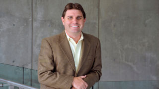 Daniel Ladik in brown suit, smiling