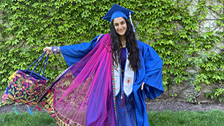 College of Education Student in her cap and gown on campus.