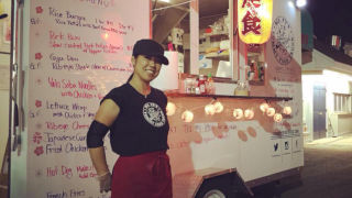 Girl in hat and apron standing in front of a food truck