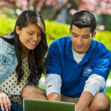 Two students using a laptop outside