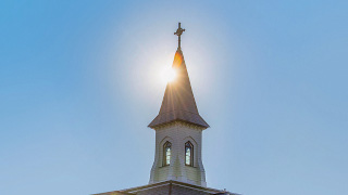 President's Hall spire with the sun in the background. 