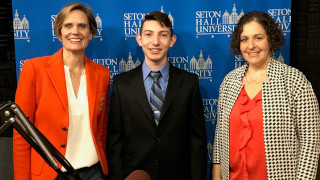 Women in a red suit jacket, boy in a black suit and woman in cheeckered jacket pose for a picture