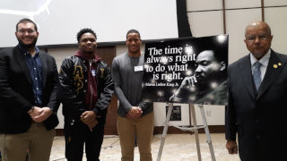 Four MLKSA members standing by a sign