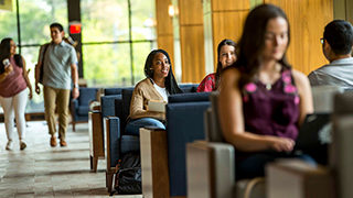 Students on campus, one student with laptop open.