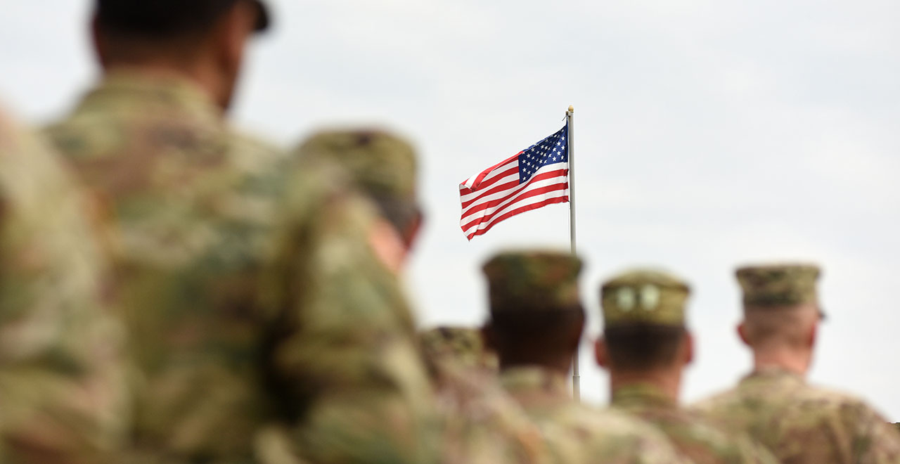 Soldiers marching with an American flag.