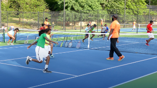 Players cover the tennis court at Branch Brook Park for the Greater Newark Tennis and Education Program, with Seton Hall Education students assisting. 