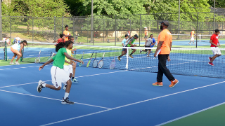 Players at Branch Brook Park. Players cover the tennis court in Branch Brook Park for the Greater Newark Tennis and Education Program, with Seton Hall education students assisting.