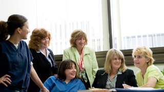 Image of nurses and health care administrators in a room smiling. 