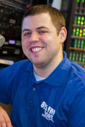 Student in blue shirt sitting in front of a microphone and switcher