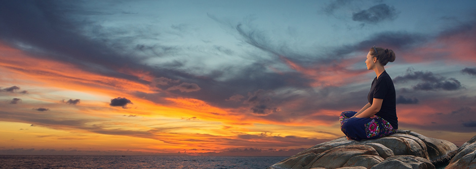 A person sitting on a mountain watching the sunset.