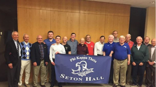 Members of Phi Kappa Theta Alumni holding a banner with a Seton Hall logo and the Phi Kappa Theta name.