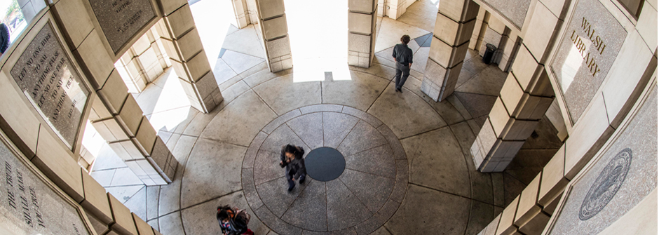 Image of the Walsh Library's rotunda from the top down with students walking through it. 