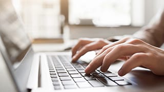 Hands typing on a laptop computer.