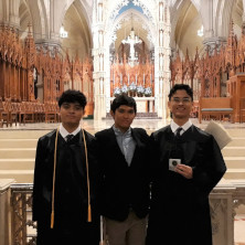 Three young males smiling for a photo in a church