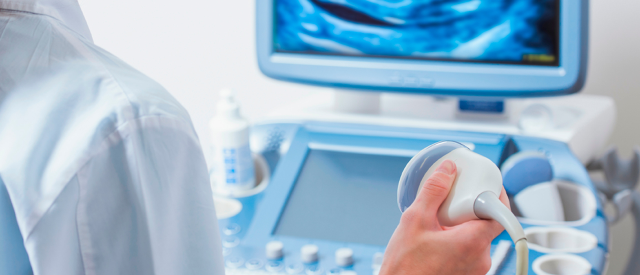 Image of a woman using an ultrasound machine with a woman of a fetus on the screen. 