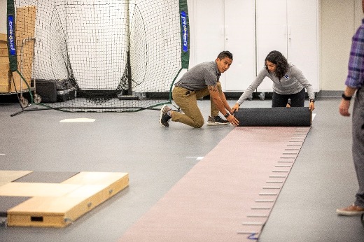 Two people rolling out a walkway.