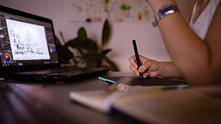 Student using a stylus on their tablet in front of an open laptop.