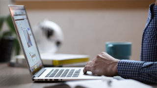 An adult typing on a laptop.