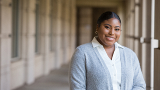 Akaysha Palmer standing in the Walsh Library walkway wearing a gray sweater.