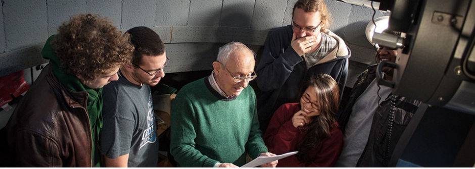 Alfred Freilich looking at a piece of paper with Giant Leap students. 