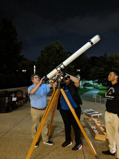 Jose Lopez looking through a telescope with students during Astronomy Week for Giant Leap.