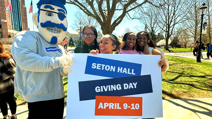 A photo of the Seton Hall Pirate with students holding a sign that reads: Seton Hall Giving Day April 9 - 10.