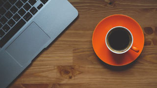 An image of a coffee mug next to a laptop. 