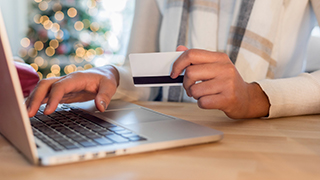 A woman holding a credit card and typing on the computer