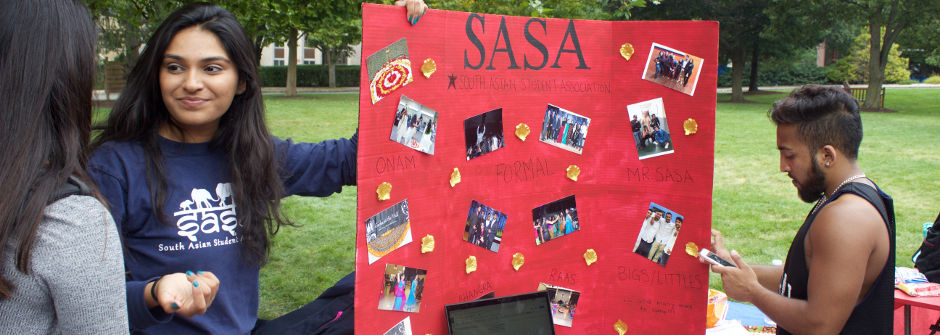 Student with a poster for the SASA club at the Involvement Fair. 