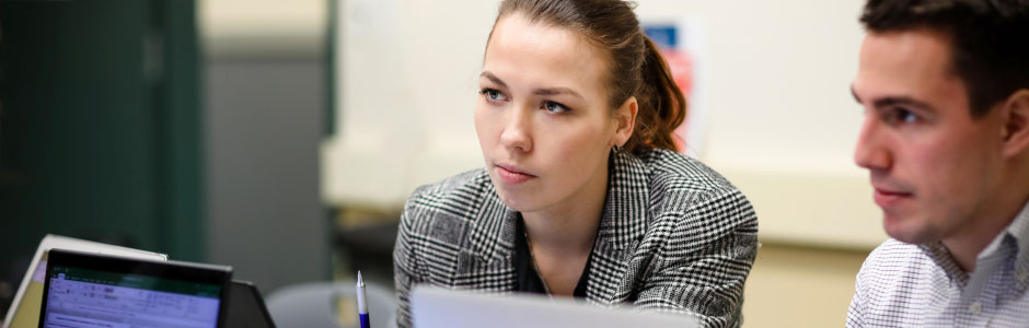 Two employees collaborating on work and using a computer